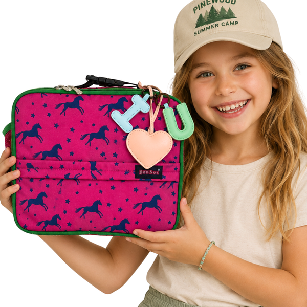 Girl holding a Yumbox pink lunch bag with horse pattern 
